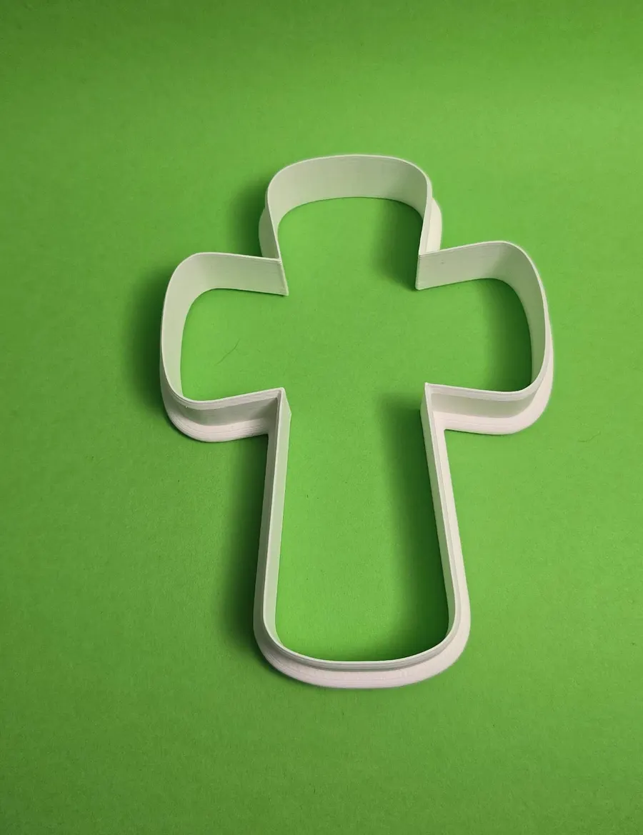 White cross-shaped cookie cutter on a green background